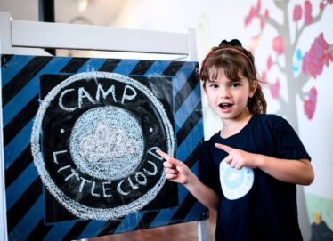 LeafSpring School student pointing to Camp Little Cloud sign